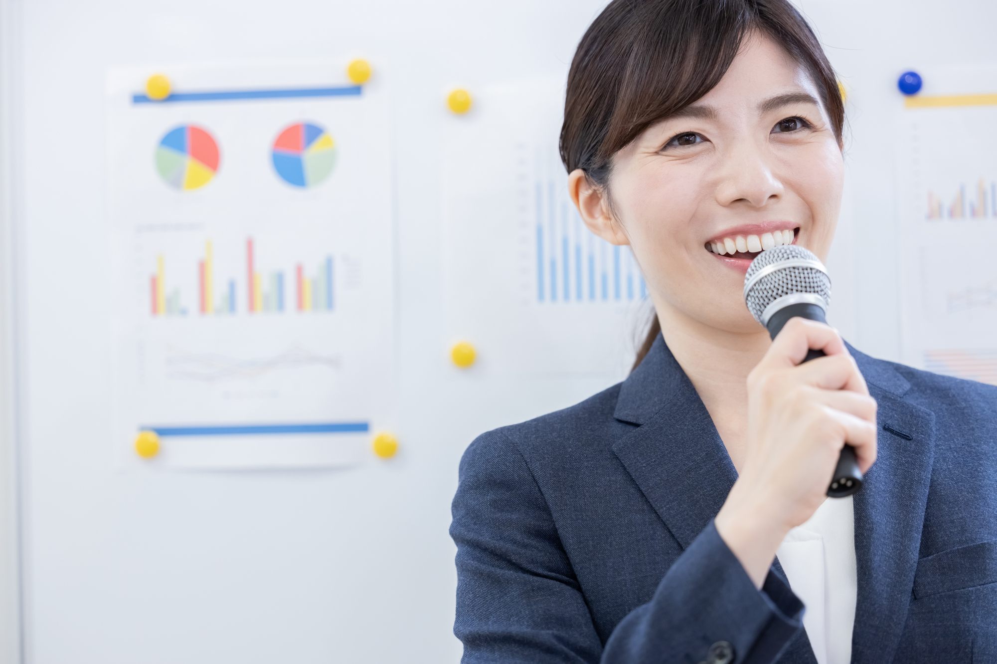 資料を掲示したホワイトボードの前でマイクを持ち話す講師